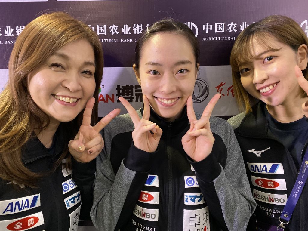 国際大会にて選手と共にピースサインをする石川久美